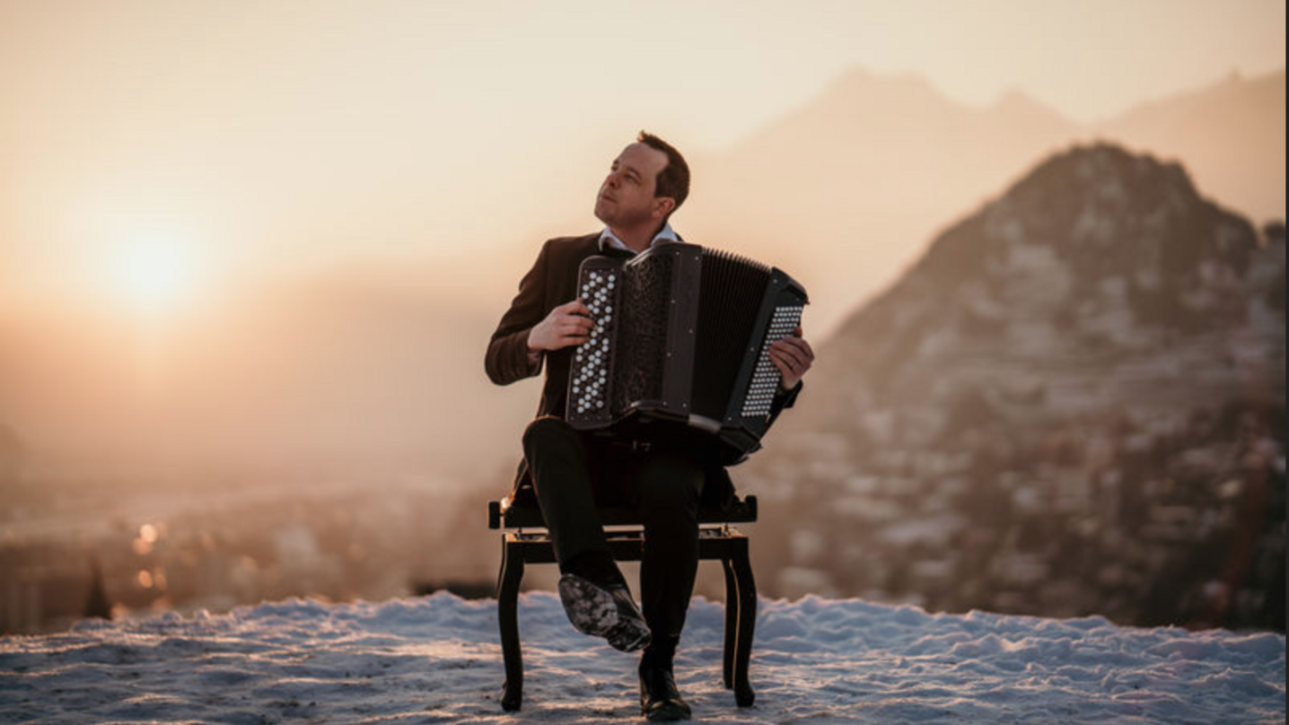 L'aacordéoniste Yves Moulin avec son instrument de musique, dans un cadre enchanteur au lever de soleil